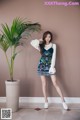 A woman standing next to a potted plant in a room.