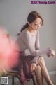 A woman sitting on a chair wearing a skirt and a sweater.