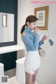 a woman in a blue sweater and white skirt looking at her cell phone