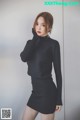 a woman in a black sweater and skirt posing for a picture