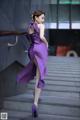 A woman in a purple dress is walking up some stairs.