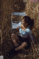 A woman sitting on a chair in a field of tall grass.