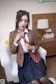 A woman in a school uniform is sitting on a white chair.