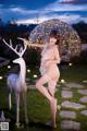 A woman in a white lingerie posing next to a white deer.