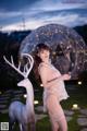 A woman in lingerie posing next to a white deer.