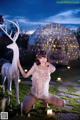 A woman kneeling down next to a white deer statue.