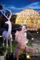 A woman in lingerie kneeling in front of a white deer.