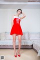 A woman in a red dress posing on a couch.