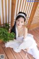 A woman in a white dress sitting on a wooden floor.