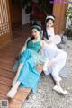 A couple of women sitting on top of a wooden bench.