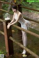 A woman in a white dress leaning on a wooden bridge.