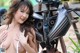 A woman in a white bikini posing next to a motorcycle.