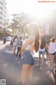 A woman in a white top and blue shorts is walking down the street.