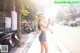 A woman in shorts and a hat is standing on the street.