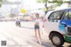 A woman standing in front of a taxi on a city street.