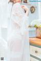 a woman in a white robe standing next to a dresser