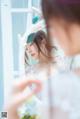 A woman in a white dress looking at herself in the mirror.