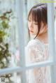 A woman in a white dress looking out of a window.