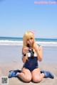 A woman in a sailor outfit sitting on the beach.