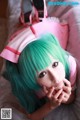 A woman with green hair wearing a pink nurse outfit.