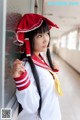 A woman in a school uniform leaning against a wall.