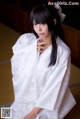 A woman in a white kimono sitting on the floor.