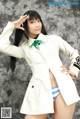 A woman in a white coat and blue panties posing for a picture.