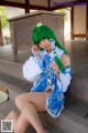 A woman with green hair sitting on a wooden bench.