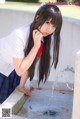 A woman in a school uniform is drinking water from a fountain.