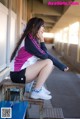 A woman sitting on a bench with her legs crossed.