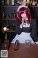 A woman dressed as a maid sitting at a bar.