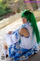 A woman with long green hair sitting on a wooden bench.