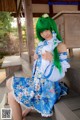 A woman with green hair sitting on a wooden bench.