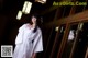 A woman in a white kimono standing in front of a building.