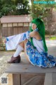 A woman with green hair sitting on a wooden bench.