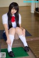 A woman in a school uniform sitting on the floor.