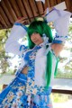 A woman with green hair wearing a blue and white outfit.