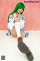 A woman with green hair sitting on a white rug.