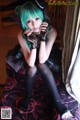 A woman with green hair sitting on a bed.