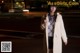 A woman standing in the middle of a street at night.