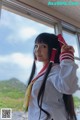 A woman in a school uniform standing by a window.