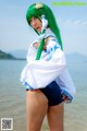 A woman with green hair standing on a beach.