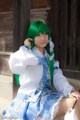 A woman with green hair sitting on a bench.