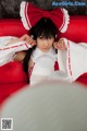 A woman in a maid outfit laying on a red couch.