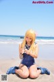 A woman in a blue bathing suit sitting on the beach.