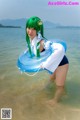 A woman with green hair is standing in the water with an inflatable ring.