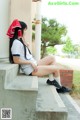 A woman sitting on the steps of a building wearing a red hat.