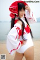 A woman in a white and red outfit posing on a beach.