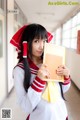 A woman in a school uniform holding a book.