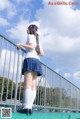 A woman in a school uniform standing on a bridge.